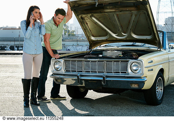 Couple looking at car engine making telephone call  Los Angeles  California  USA
