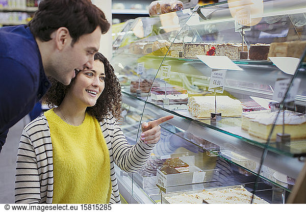 Couple looking at desserts in bakery display case
