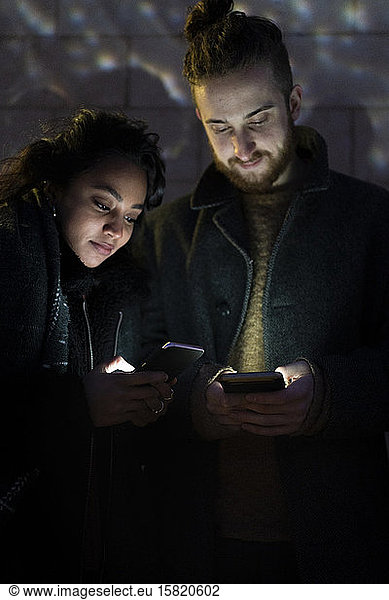 Couple looking at illuminated smartphones in the dark