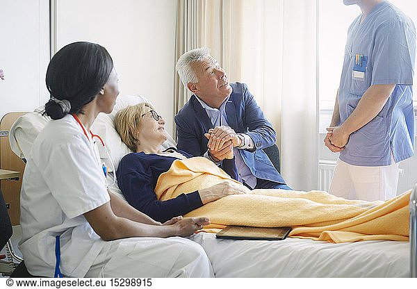 Couple looking at medical professionals in hospital ward