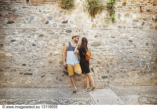 Couple looking face to face while leaning on wall