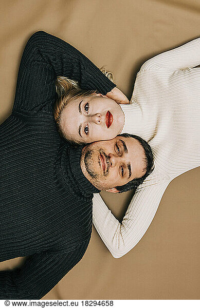 Couple lying down on brown backdrop