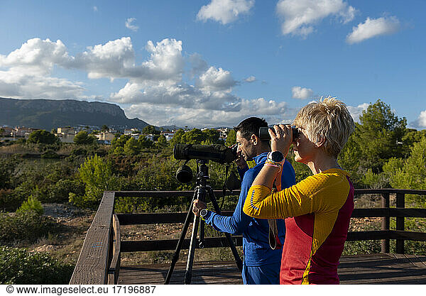 Couple of birdwatchers using binoculars and telescope.