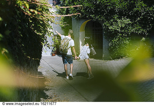 Couple of tourists walking through alley of village