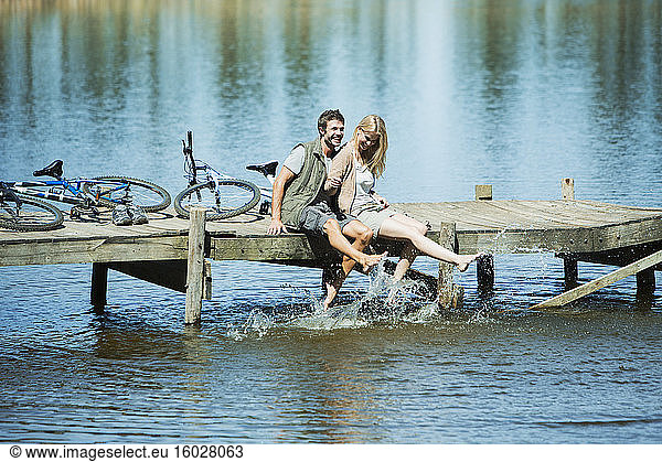 Couple on dock splashing feet in lake