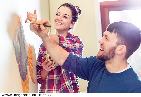 Couple painting wall mural smiling