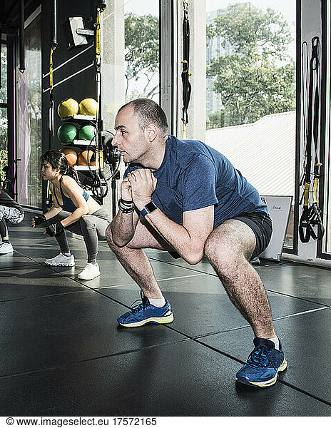couple performing warm up squads at gym in Bangkok