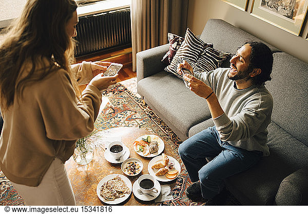 Couple photographing breakfast with smart phones in hotel room