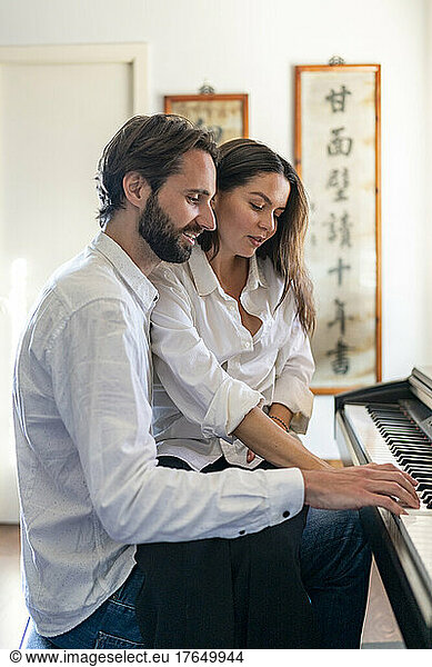 Couple playing piano sitting next to each other