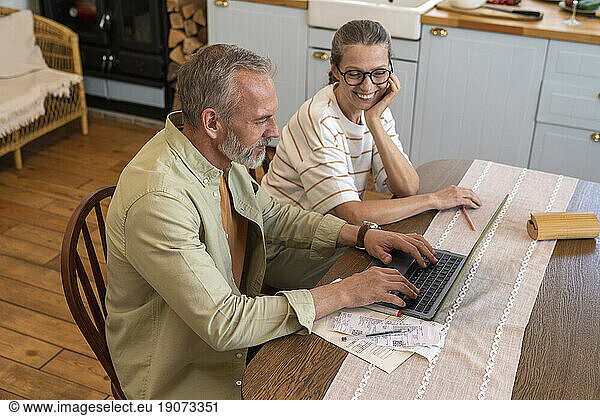 Couple preparing financial bills using laptop at home