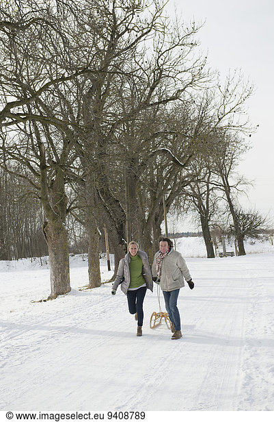 Couple pulling sledge in snow