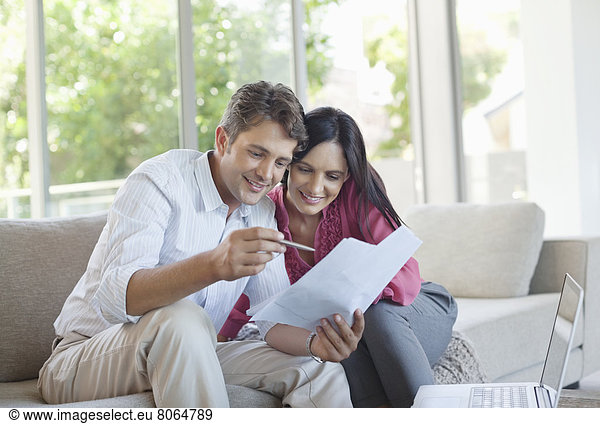 Couple reading papers together on sofa