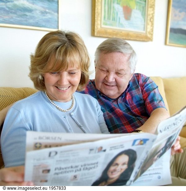 Couple reading the newspaper in couch