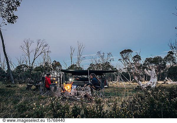 Couple relaxing at campfire in Alpine National Park Australia