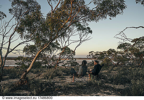 Couple relaxing in camping chairs among trees  Australia