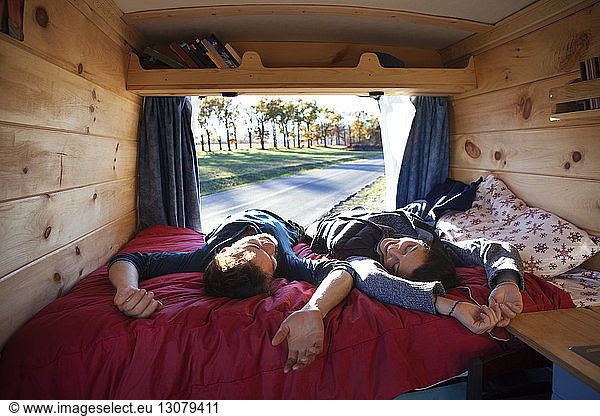 Couple relaxing on bed in camper van