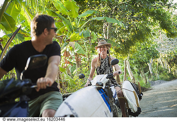 Couple riding on motorbikes with surfboards  Nusa Lembongan  Indonesia
