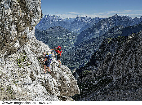 Couple rock climbing on sunny day at Dolomiti Bellunesi National Park Forcella Comedon  Dolomites  Italy