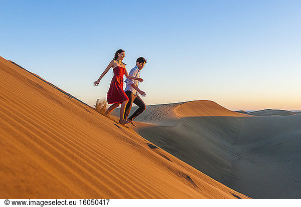 Couple running down dunes at sunset  Gran Canaria  Spain