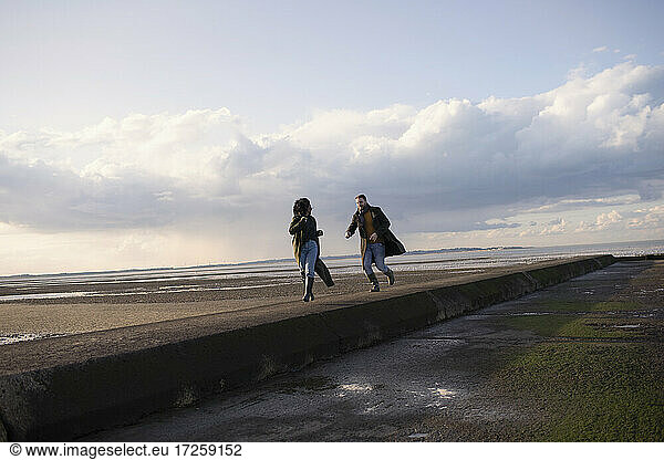 Couple running on ocean beach jetty