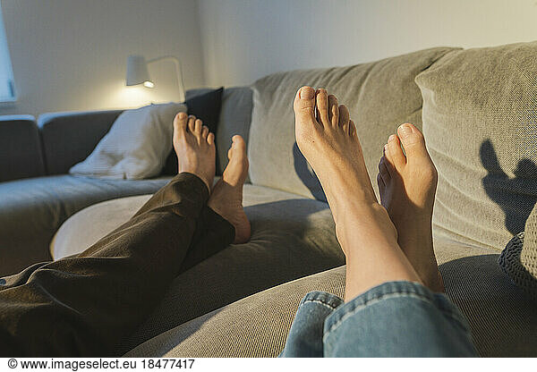 Couple's legs resting on sofa in living room