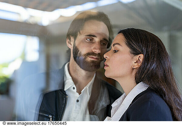 Couple separated through glass pane looking at each other