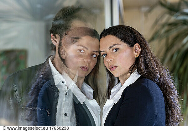 Couple separated through glass pane  woman looking at camera