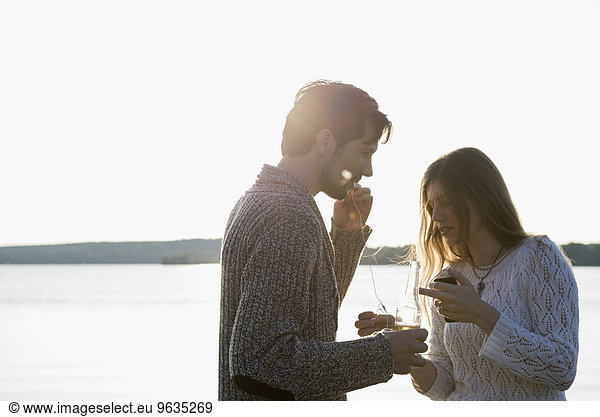 Couple sharing cell phone music drinking beer
