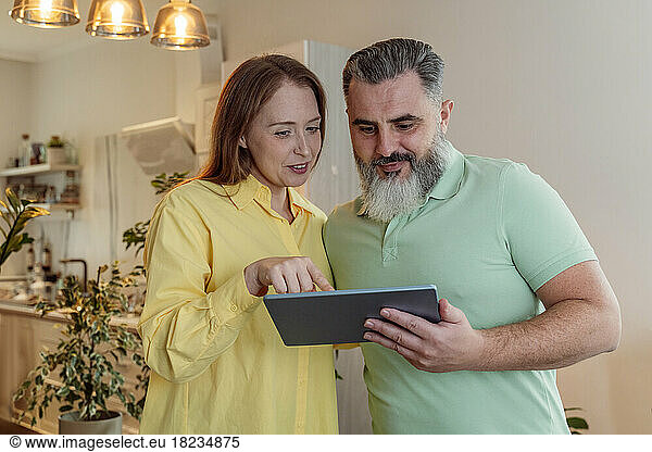Couple sharing tablet PC standing at home
