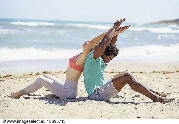 Couple sitting and stretching arms at beach