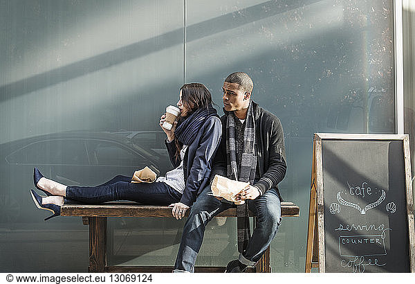 Couple sitting on bench outside cafe shop