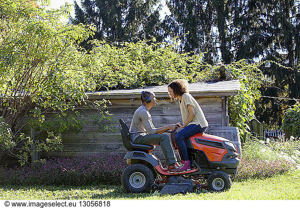 Couple sitting on riding mower at farm