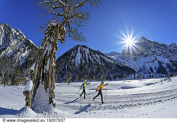 Couple skiing on snow covered landscape by Karwendel Mountains