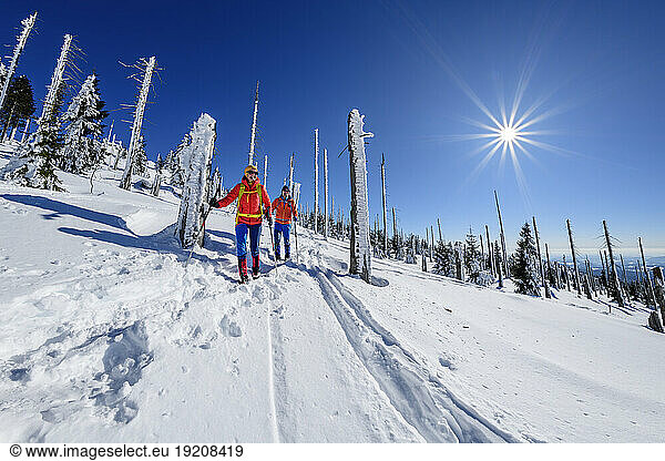 Couple skiing on snow covered landscape on sunny day