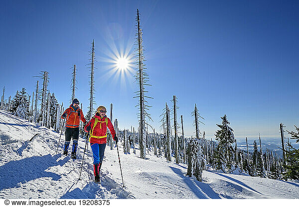 Couple skiing on snowcapped landscape on sunny day