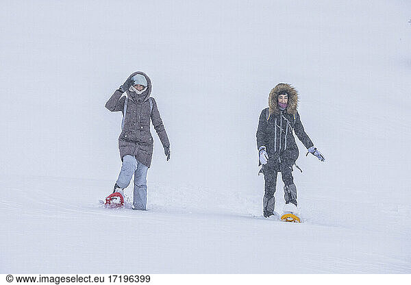 couple snowshoeing through snowy field