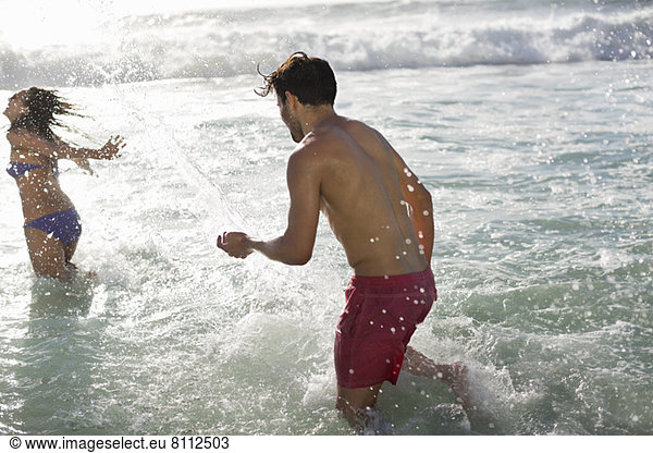 Couple splashing in ocean