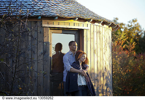 Couple standing by yurt during sunset