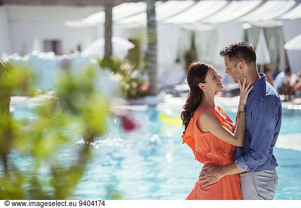 Couple standing face to face by swimming pool