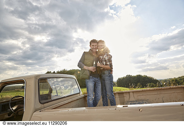 Couple standing on pick up truck with beer bottles