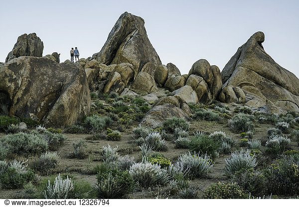 Couple standing on rocks of the Alabama Hills after sunset; California  United States of America