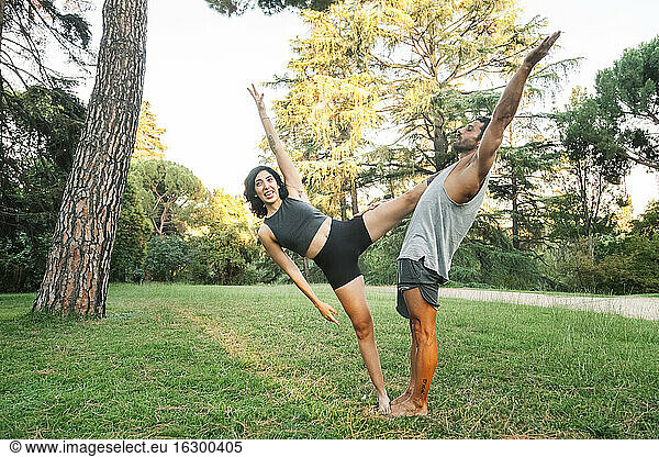 Couple stretching while doing acroyoga in public park