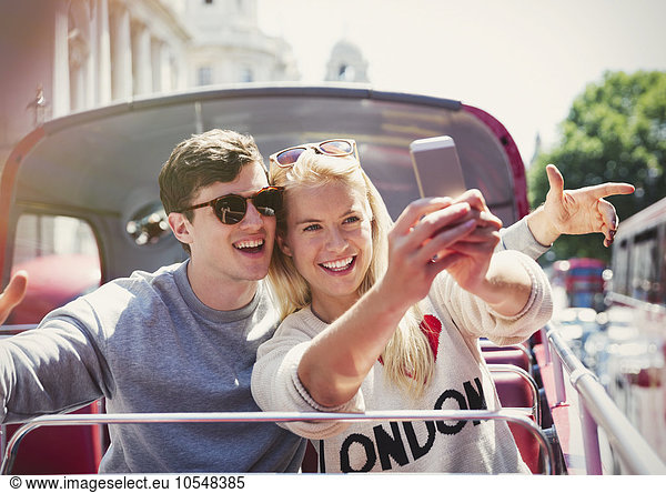 Couple taking selfie on double-decker bus in London