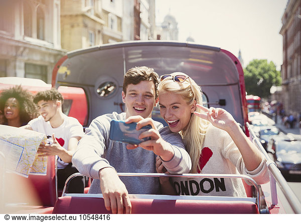 Couple taking selfie on double-decker bus  London  United Kingdom