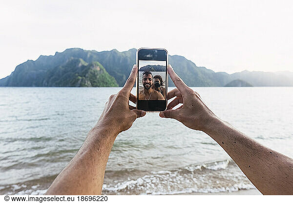 Couple taking selfie through smart phone at vacation