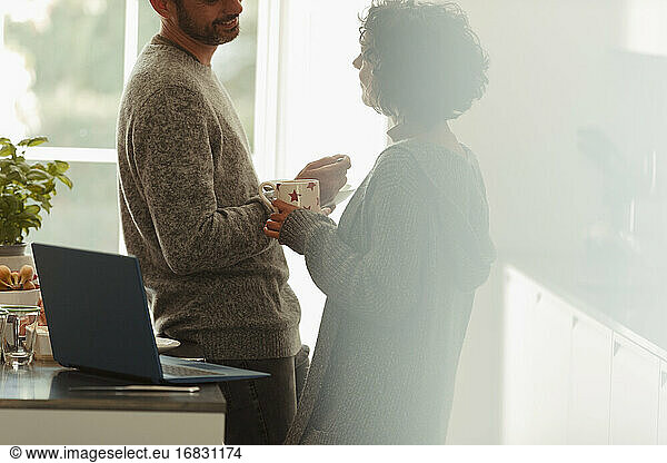 Couple talking at laptop in morning kitchen