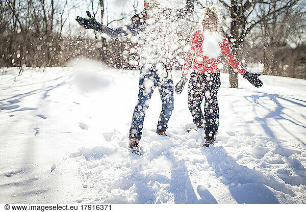 Couple throwing snowball at the camera in park.