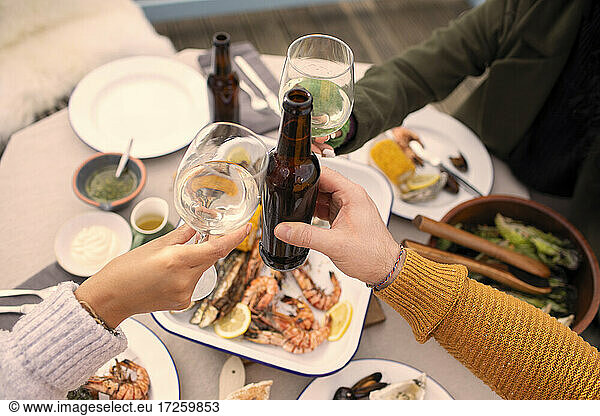 Couple toasting wine and beer over seafood lunch