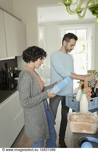 Couple unloading groceries in kitchen