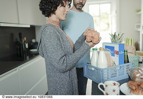 Couple unpacking groceries at kitchen counter